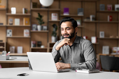 ein Mann sitzt an einem Tisch mit einem Laptop in einem Klassenraum