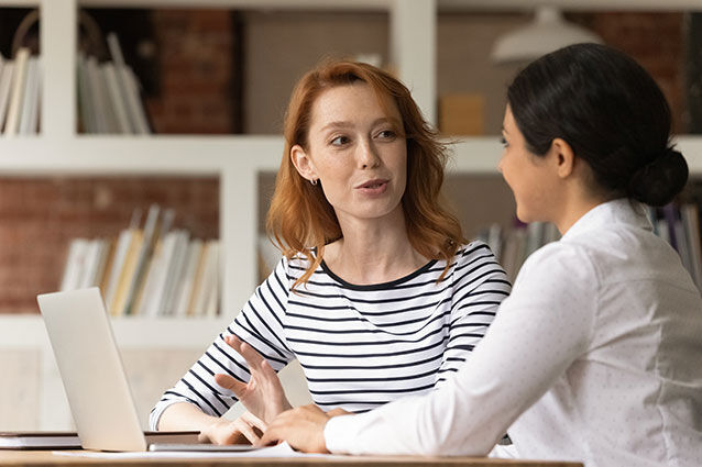 zwei Frauen sitzen an einem Tisch mit Laptops