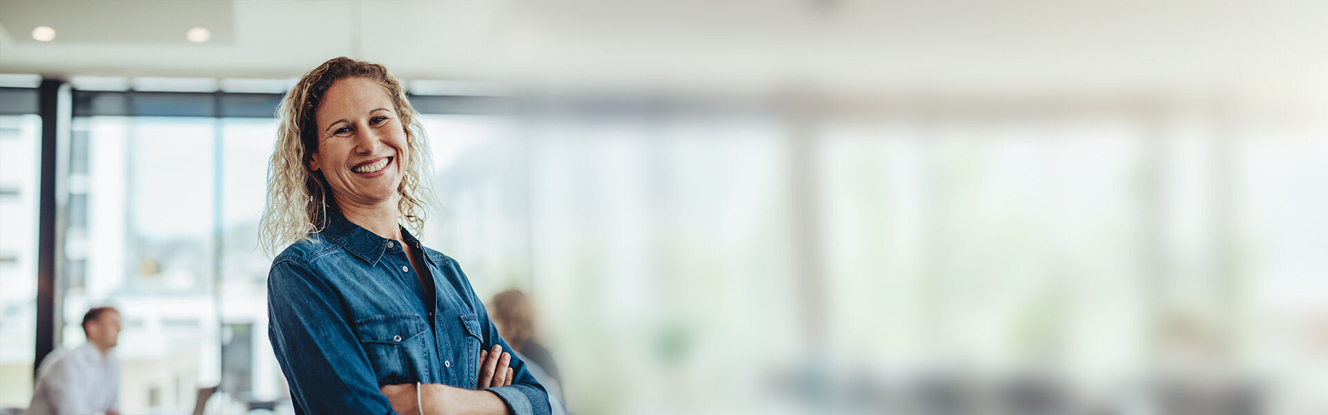 eine Frau, die mit verschrenkten Armen in einem Büro steht