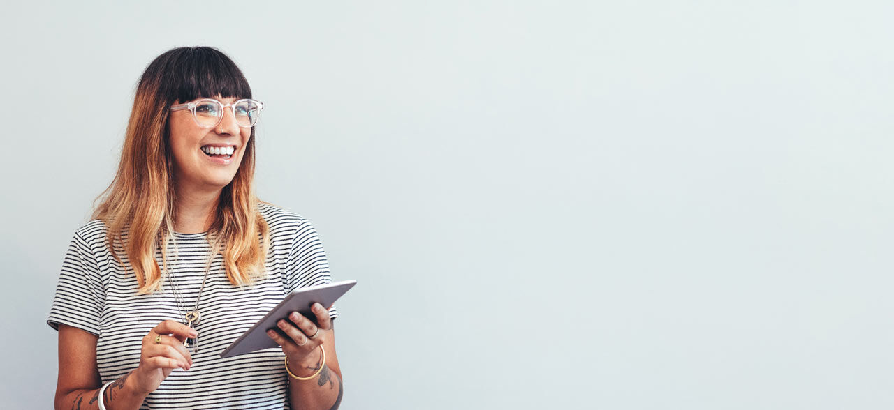 eine Frau in der Brille hält eine Tablette und lächelnd